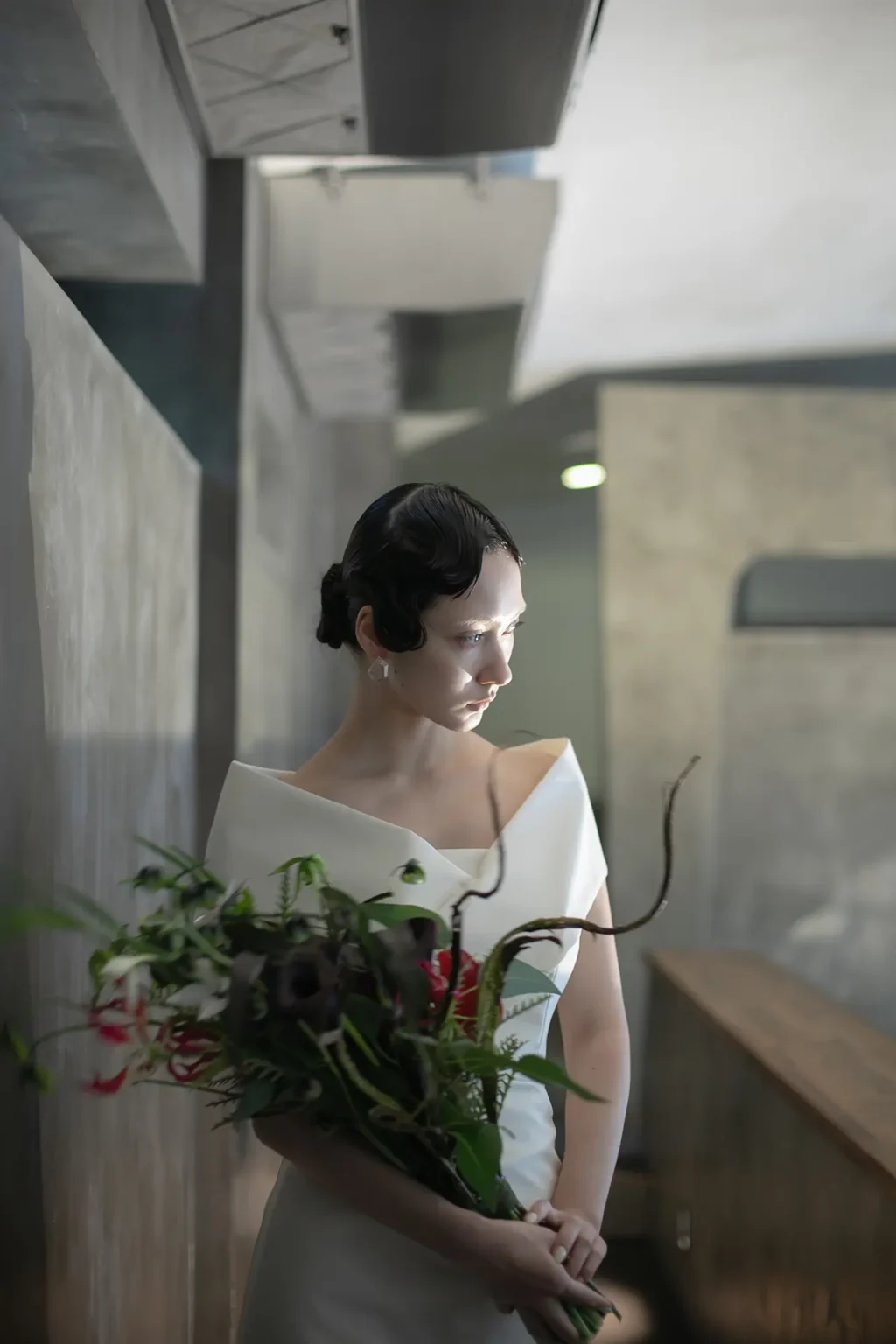 nae. ATELIERナエアトリエのシンプルで印象的なマーメイドラインのウェディングドレスを着て赤い花のブーケを持った女性