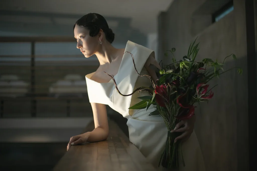nae. ATELIERナエアトリエのシンプルで印象的なマーメイドラインのウェディングドレスを着て赤い花のブーケを持った女性
