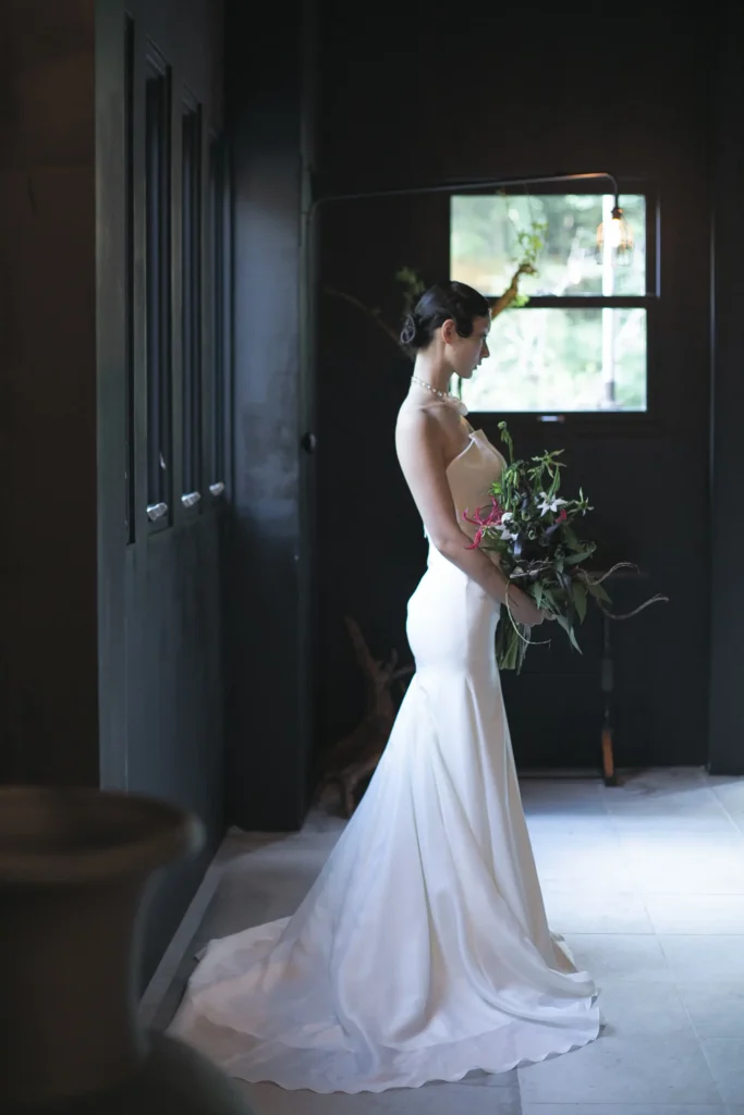 腰からヒップラインにかけての曲線美を美しく⾒せ、縦⻑のシルエットを強調するマーメイドラインのドレスを着た女性