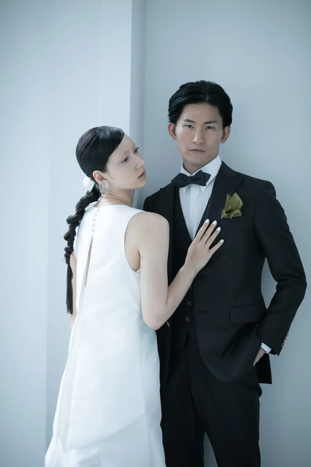 スレンダーラインのモードなウェディングドレスを着た女性とタキシードを着た新郎