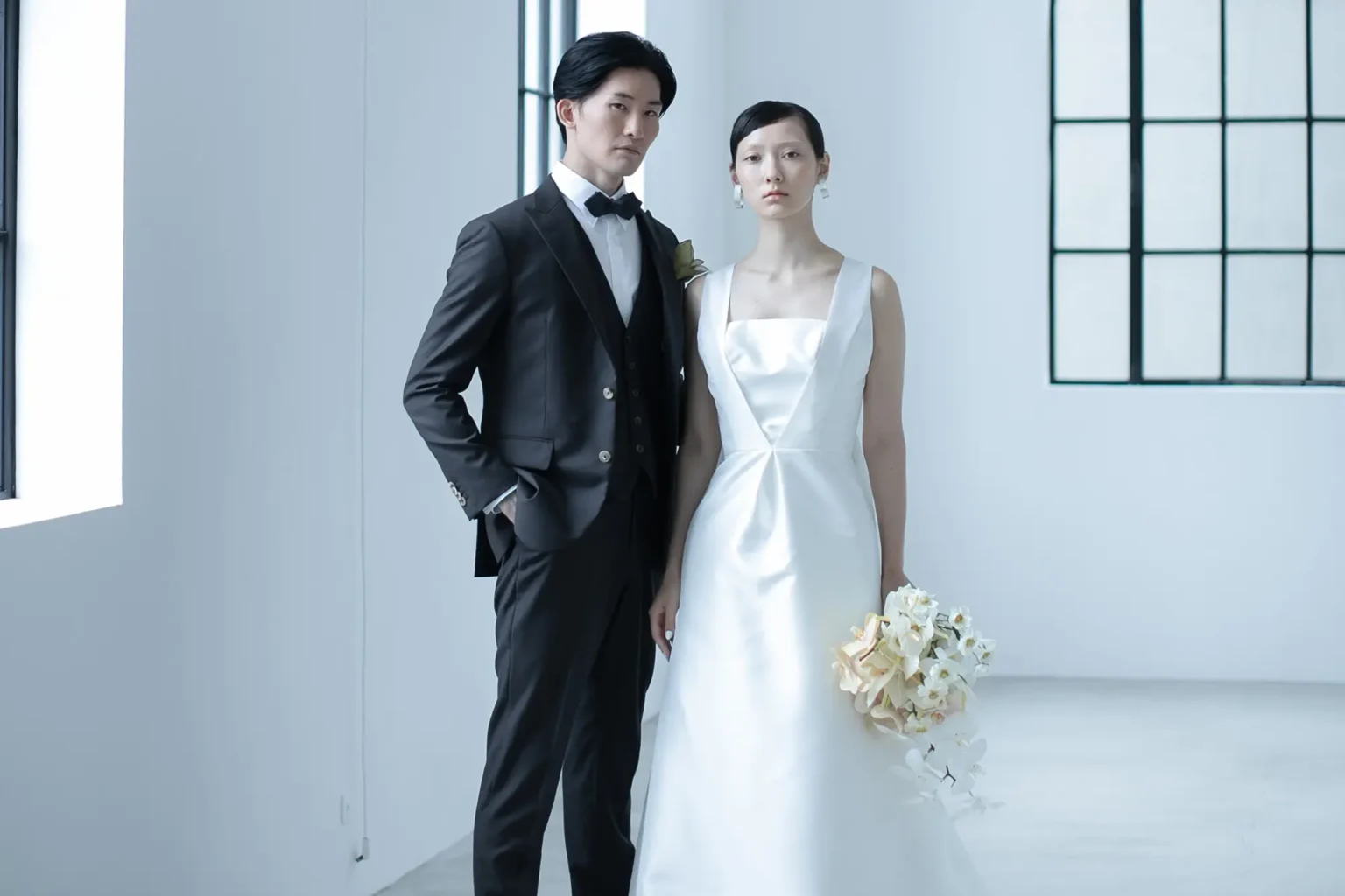 スレンダーラインのモードなウェディングドレスを着た女性とタキシードを着た新郎