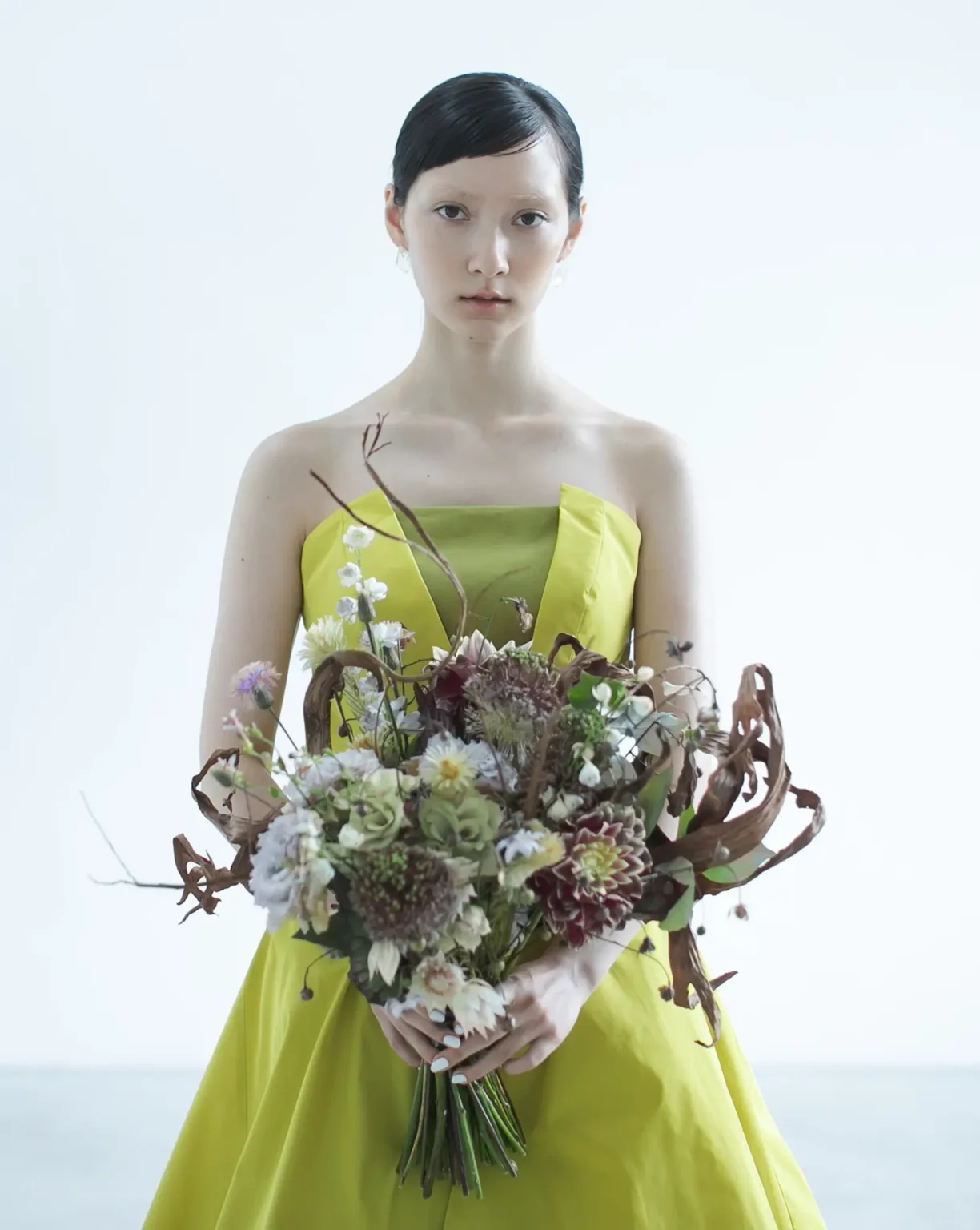 鮮やかなイエローのカラードレスを着てブーケを持つ新婦