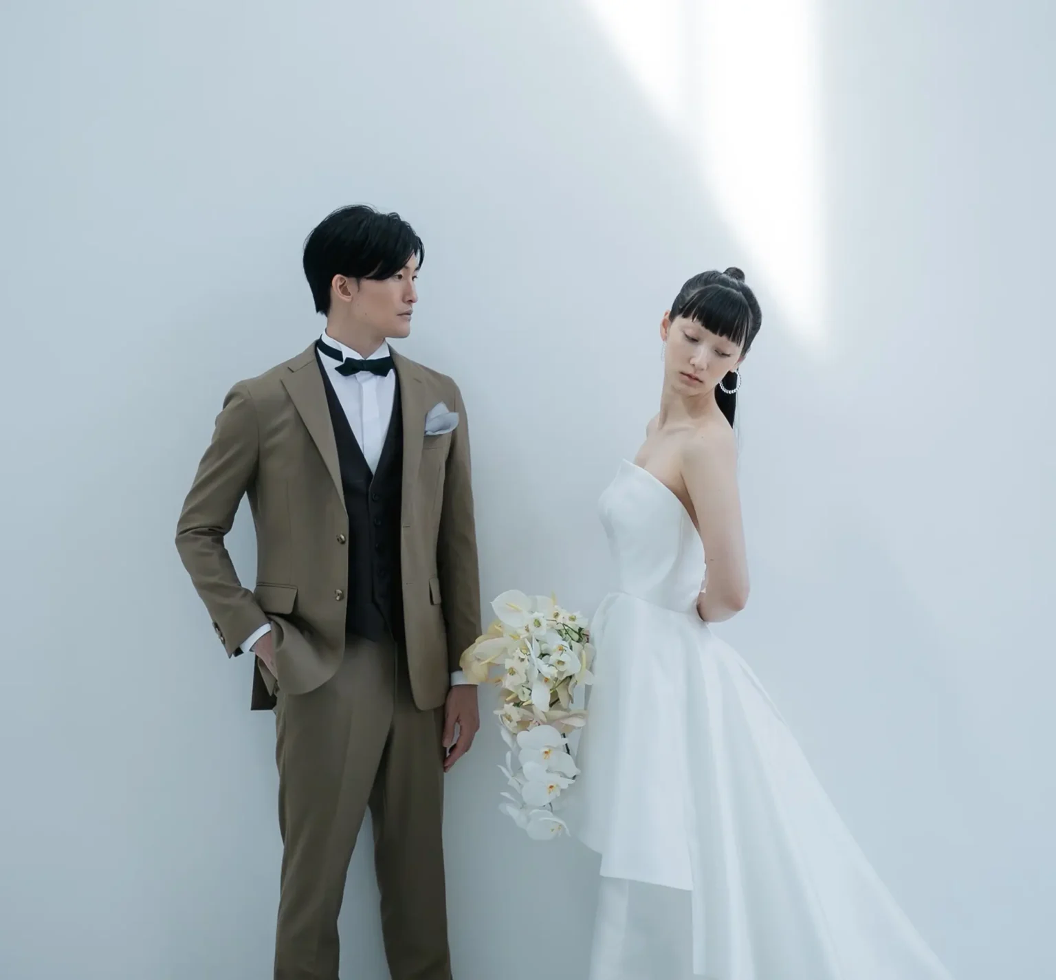 艶やかでハリが美しいミカドシルクでおつくりした、個性と華やかさを感じるドレスを着た新婦とブラウンのスーツの新郎