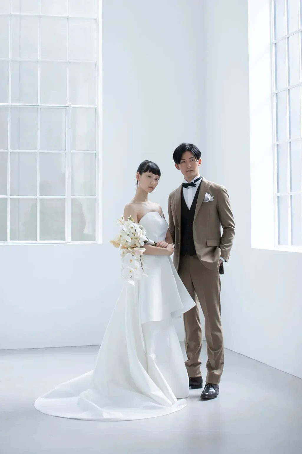 艶やかでハリが美しいミカドシルクでおつくりした、個性と華やかさを感じるドレスを着た新婦とブラウンのスーツの新郎