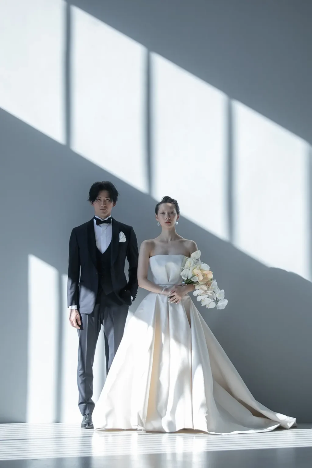 上品な光沢を持つダブルサテンで作られたつ王道かつスタイリッシュな印象のAラインドレスを着た新婦とタキシード姿の新郎