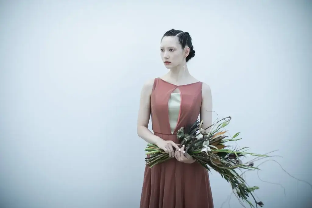 ダークオレンジのカラードレスを着てスタイリッシュなブーケを持つ花嫁