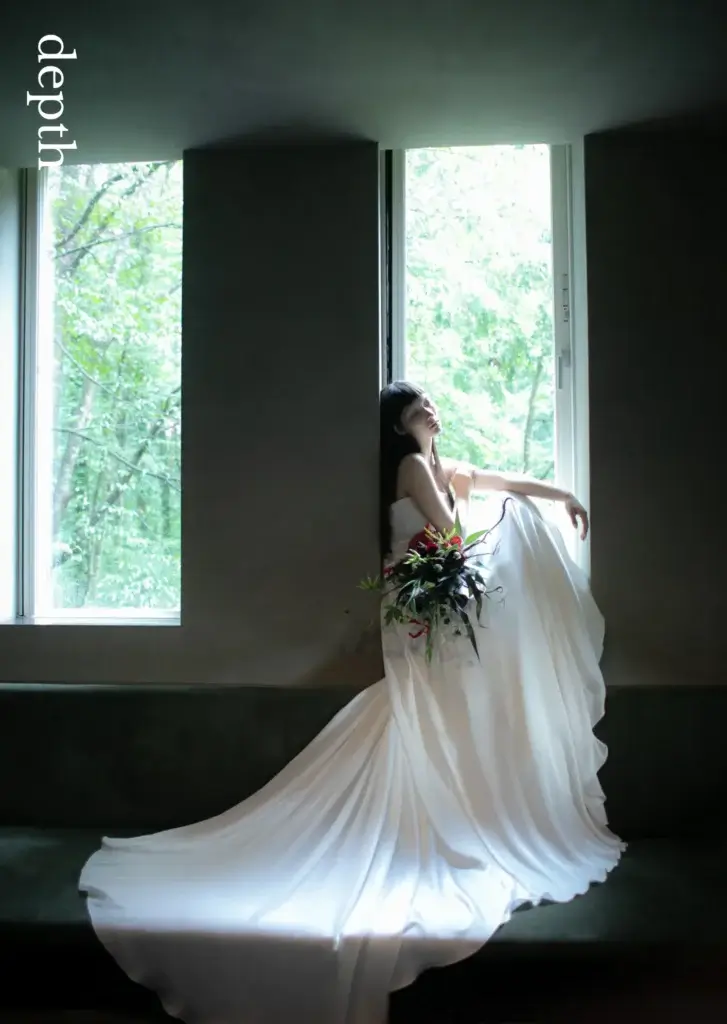 nae. ATELIERナエアトリエのウェディングドレスを着て窓辺に座って撮影する花嫁