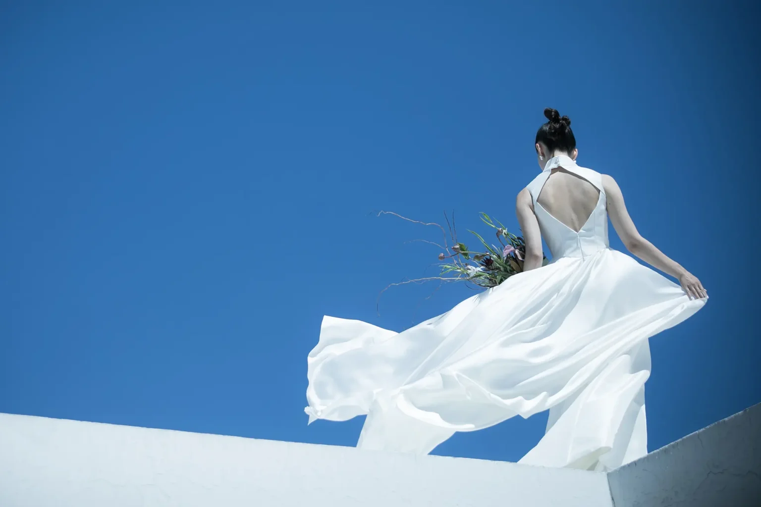 マニッシュなストレートラインのシルエットに、 華やかな余韻をたなびかせるトレーンを持つ個性的なドレス