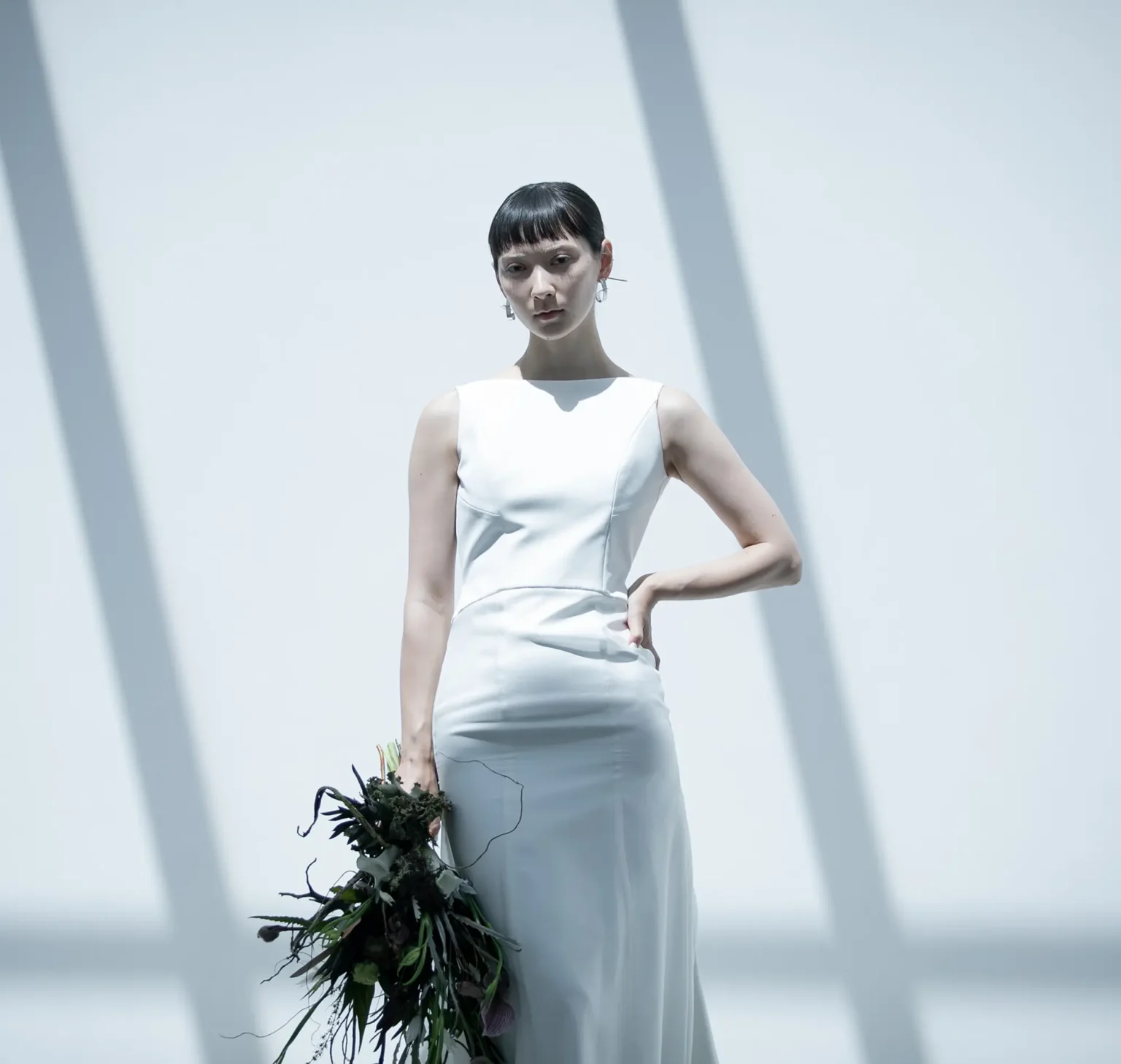 直線的でスタイリッシュなネックラインとアームホールのラインが、 鎖骨と肩の骨格を美しく印象的に見せるマーメイドラインのウェディングドレス