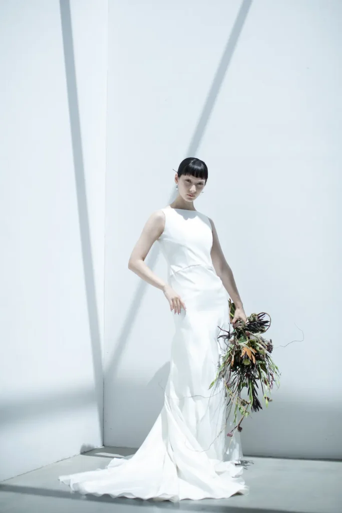 直線的でスタイリッシュなネックラインとアームホールのラインが、 鎖骨と肩の骨格を美しく印象的に見せるマーメイドラインのウェディングドレス