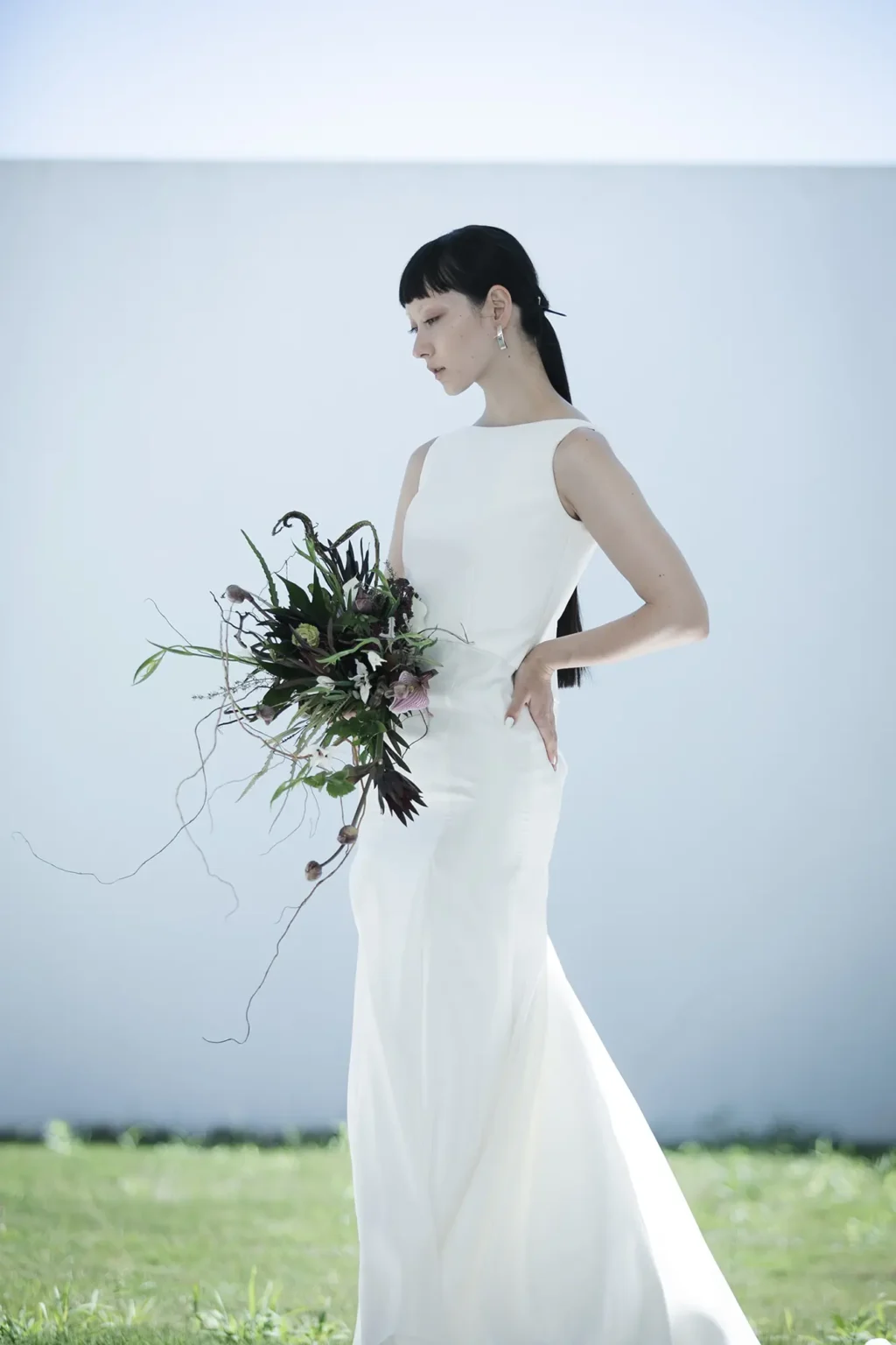 直線的でスタイリッシュなネックラインとアームホールのラインが、 鎖骨と肩の骨格を美しく印象的に見せるマーメイドラインのウェディングドレス