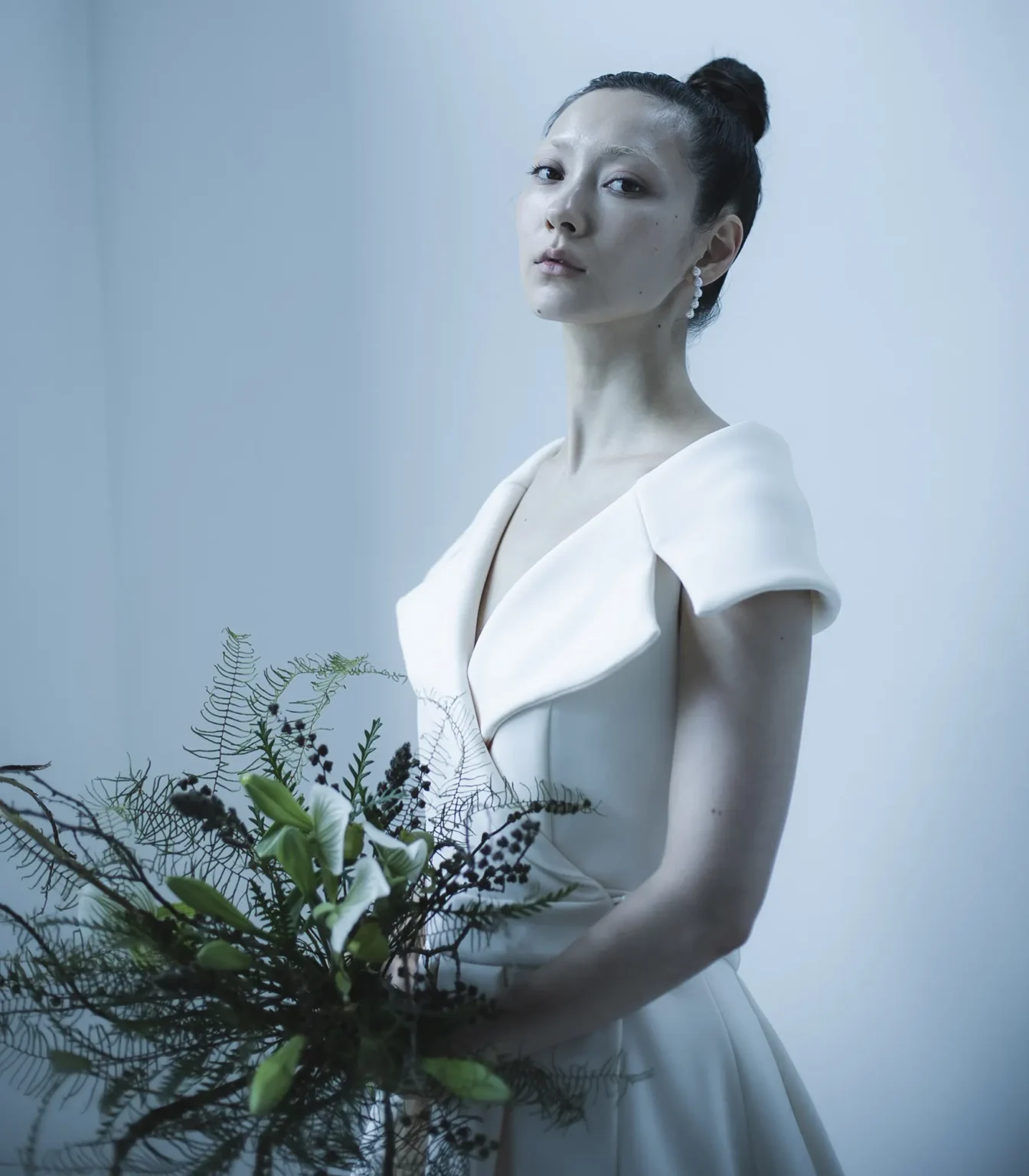 ジャケットのノッチドラペルとダブルのスーツをイメージソースに 女優のような色香と風格を醸し出す、 ウエディングドレスには珍しい ガウンを羽織るようなラップ型Aラインドレスに仕立てたドレス。