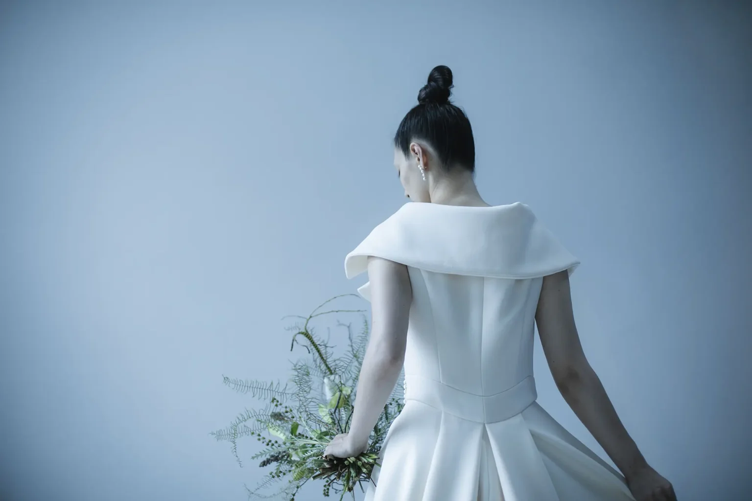 ジャケットのノッチドラペルとダブルのスーツをイメージソースに 女優のような色香と風格を醸し出す、 ウエディングドレスには珍しい ガウンを羽織るようなラップ型Aラインドレスに仕立てたドレス。