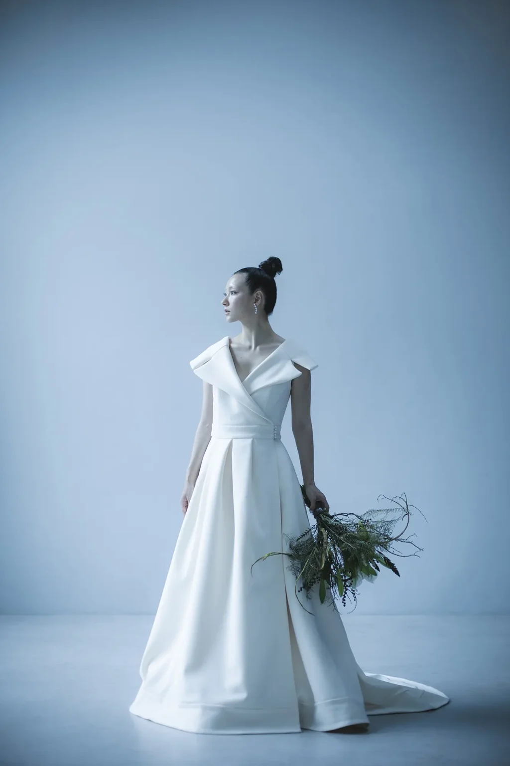 ジャケットのノッチドラペルとダブルのスーツをイメージソースに 女優のような色香と風格を醸し出す、 ウエディングドレスには珍しい ガウンを羽織るようなラップ型Aラインドレスに仕立てたドレス。