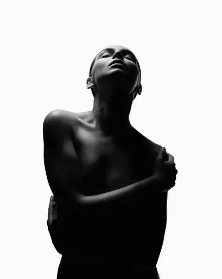 腕を体に回して顔を上にあげた女性のモノクロ写真