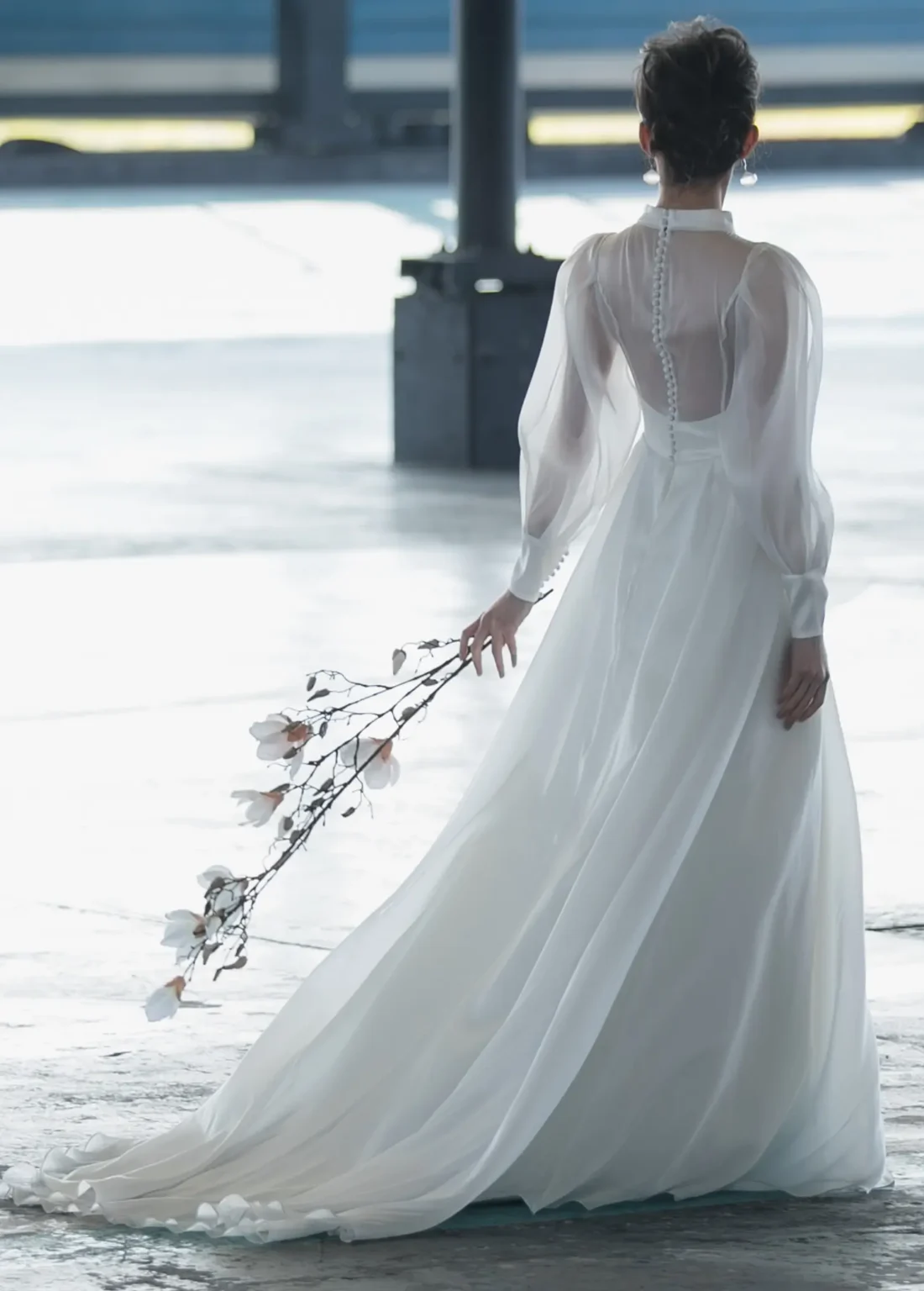 木蓮の花を持ってシースルーの長袖のウェディングドレスを着た女性