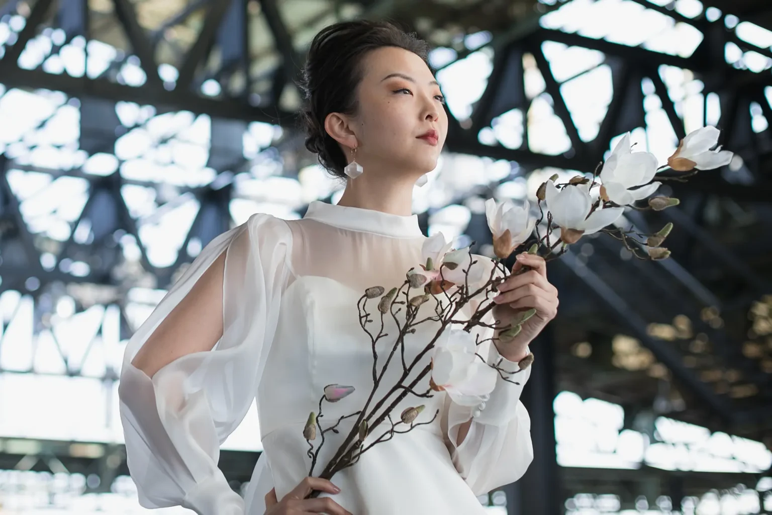 木蓮の花を持ってシースルーの長袖のウェディングドレスを着た女性