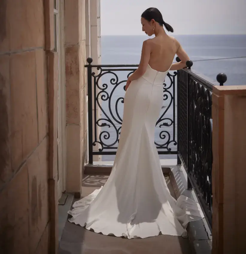 海沿いのホテルのベランダでマーメイドスタイルのウェディングドレスを着て撮影をする女性