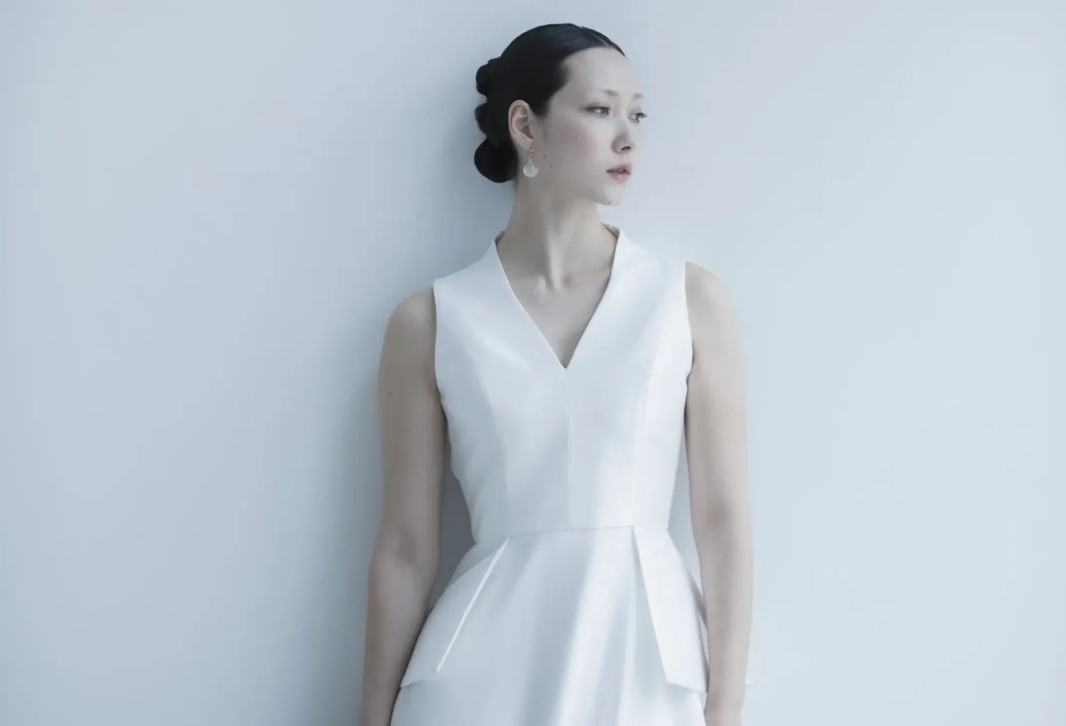 シンプルなVネックのウェディングドレスを着て佇む花嫁