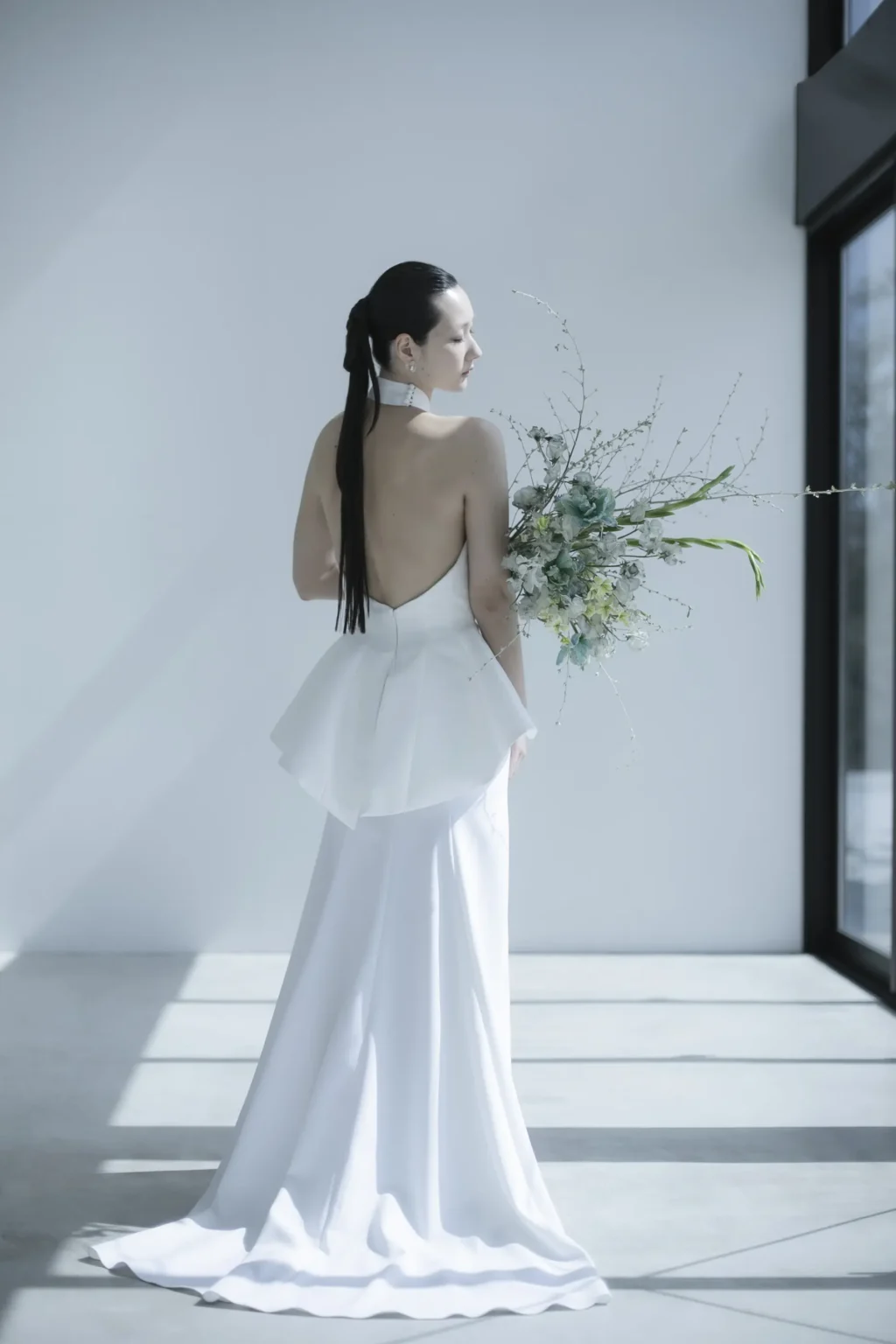 ペプラムデザインが特徴のバックラインが美しいウェディングドレスを着た花嫁